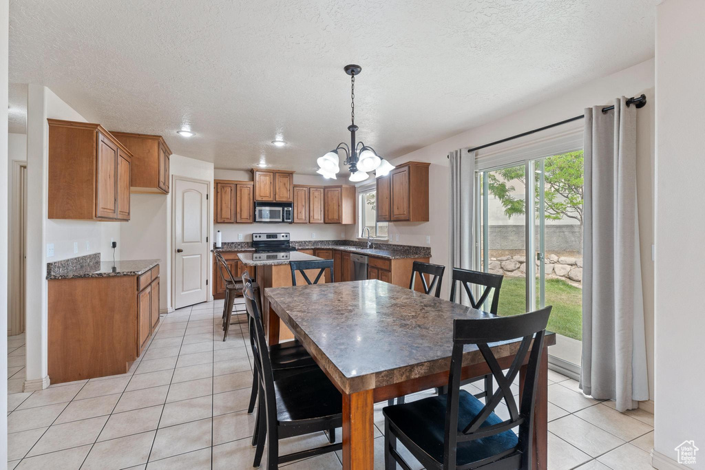 Dining space featuring a textured ceiling, a chandelier, and light tile patterned flooring