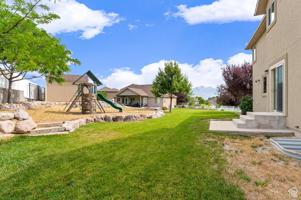 View of green lawn with a playground, a residential view, and a mountain view