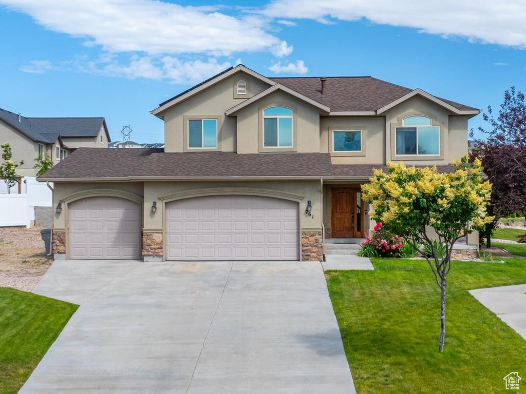 View of front facade with stucco siding, stone siding, concrete driveway, a garage, and an attached garage
