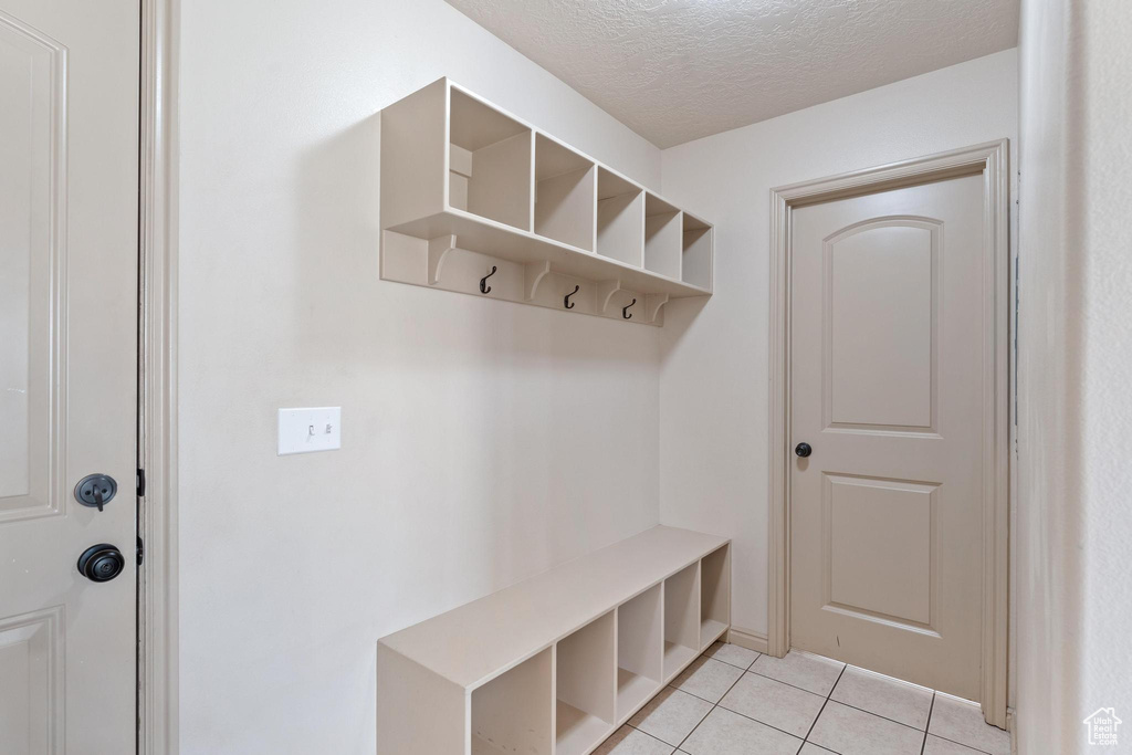 Mudroom with a textured ceiling and light tile patterned flooring