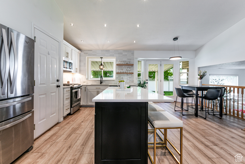 Kitchen featuring stainless steel appliances, light wood-type flooring, a kitchen island, french doors, and healthy amount of natural light