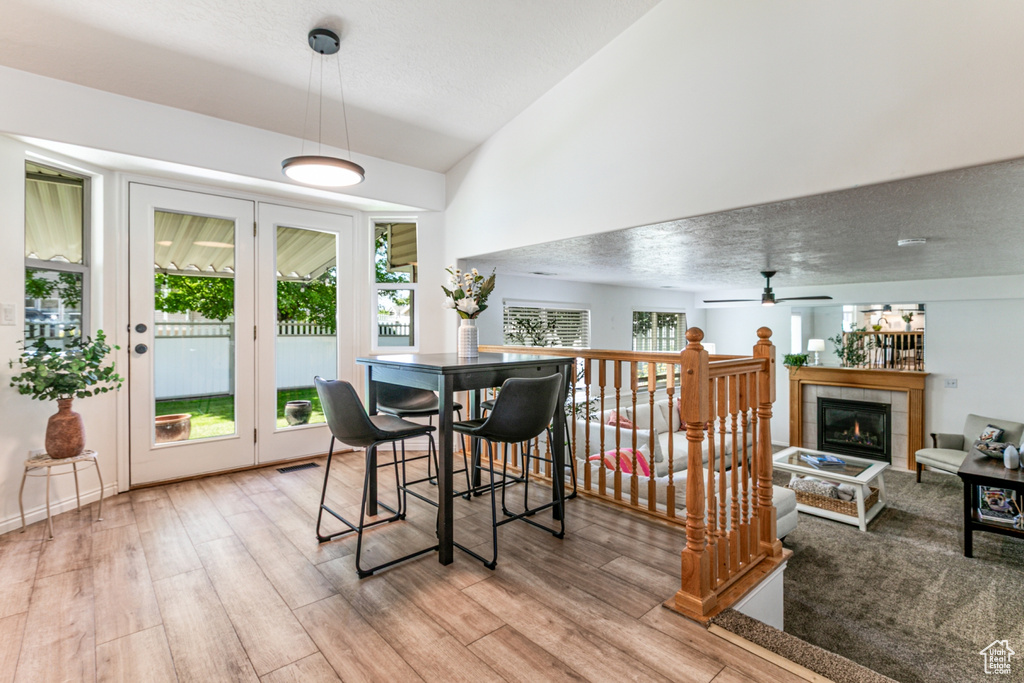 Dining area featuring a fireplace, plenty of natural light, ceiling fan, light wood-style floors, and high vaulted ceiling