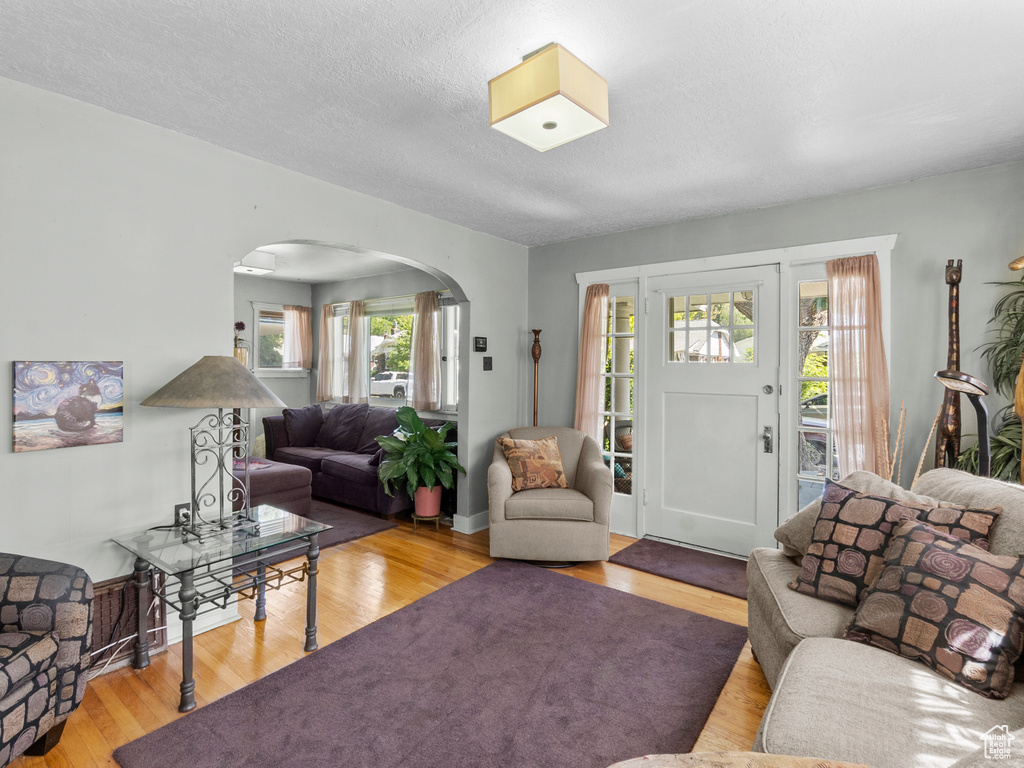 Living area with arched walkways, wood finished floors, and a textured ceiling