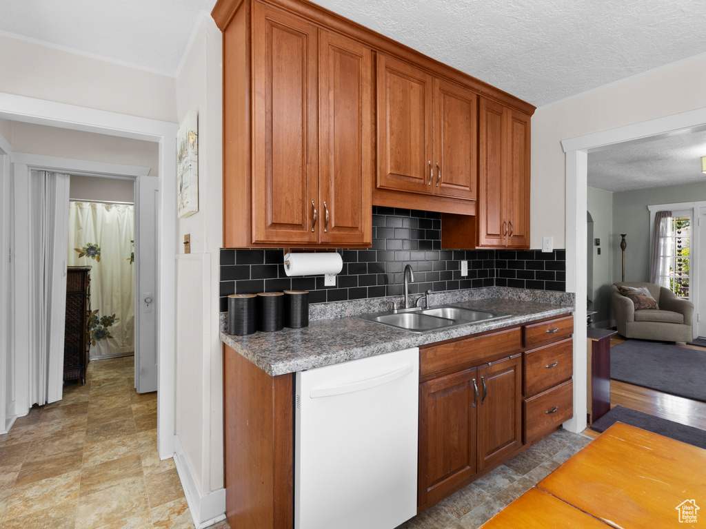 Kitchen featuring white dishwasher, decorative backsplash, and brown cabinetry