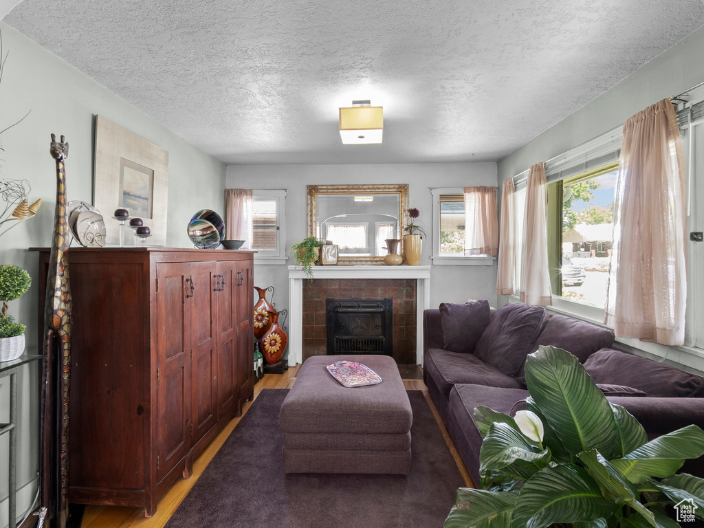 Living area featuring a textured ceiling, a fireplace, and wood finished floors