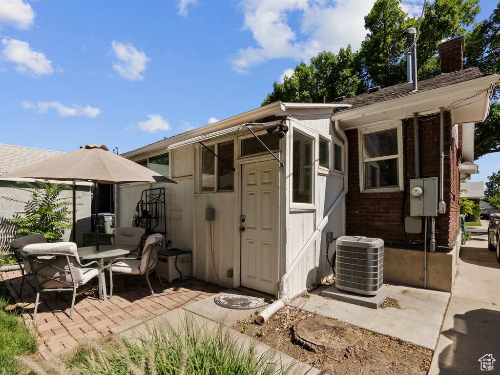 Rear view of house featuring a patio area, a chimney, and brick siding