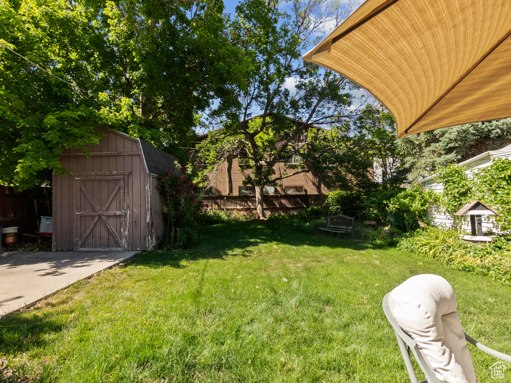 View of grassy yard featuring a storage unit