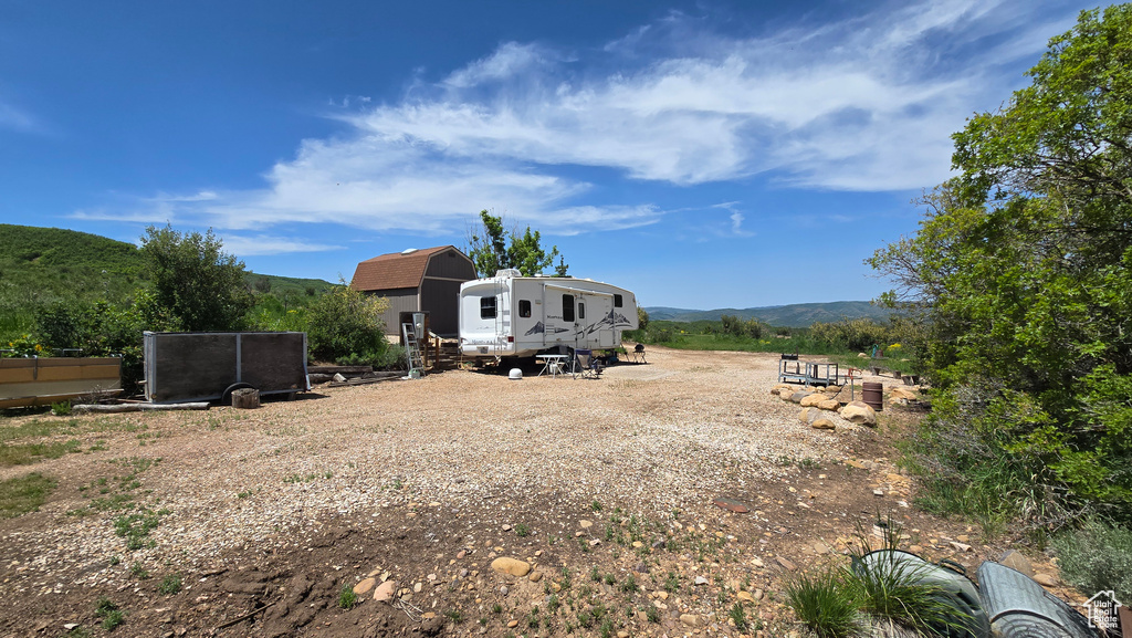 Back of house with a gambrel roof, a mountain view, and an outdoor structure