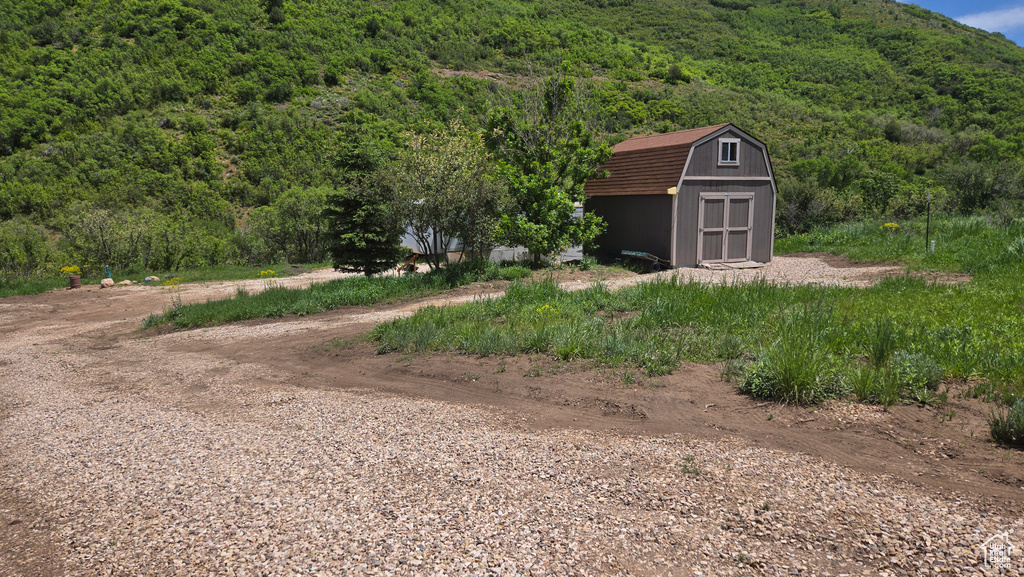 View of yard featuring a storage shed and a wooded view