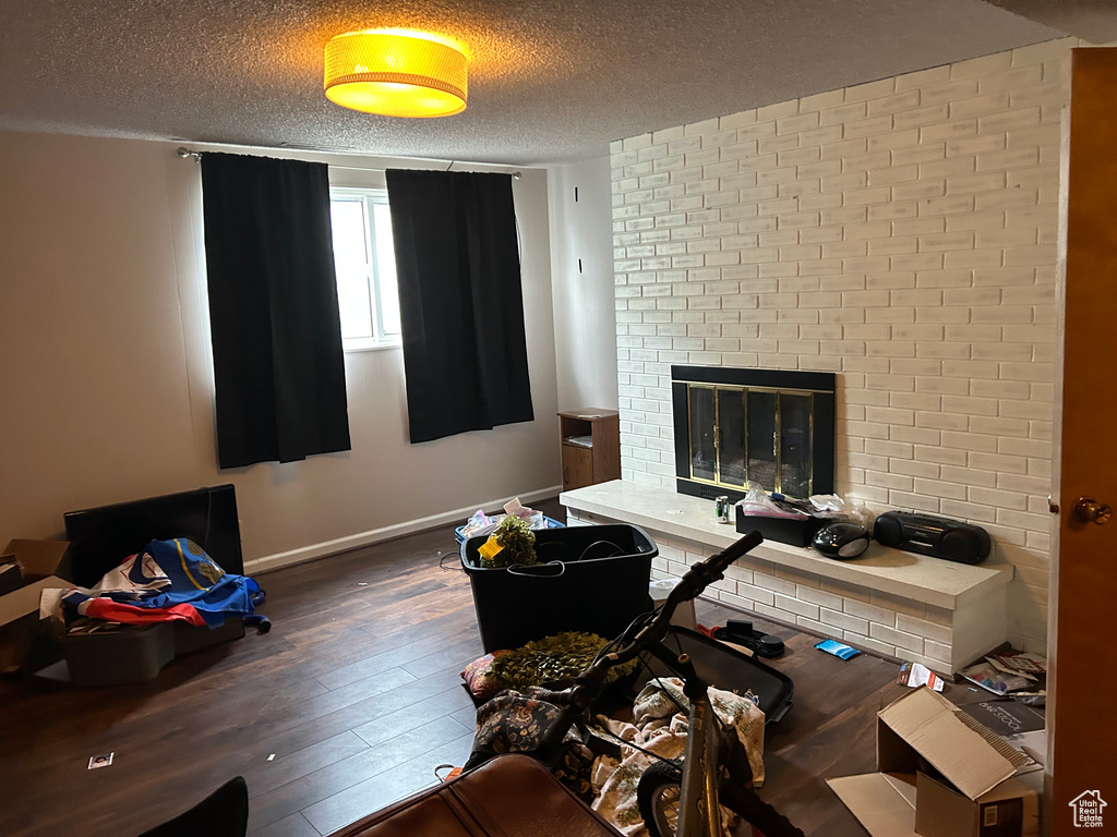 Office area featuring hardwood / wood-style flooring, a textured ceiling, baseboards, and a brick fireplace