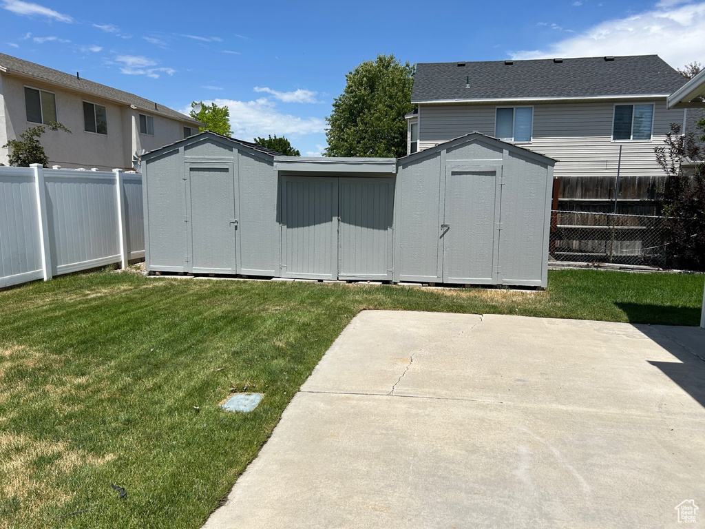 Fenced backyard featuring a storage shed and a patio area