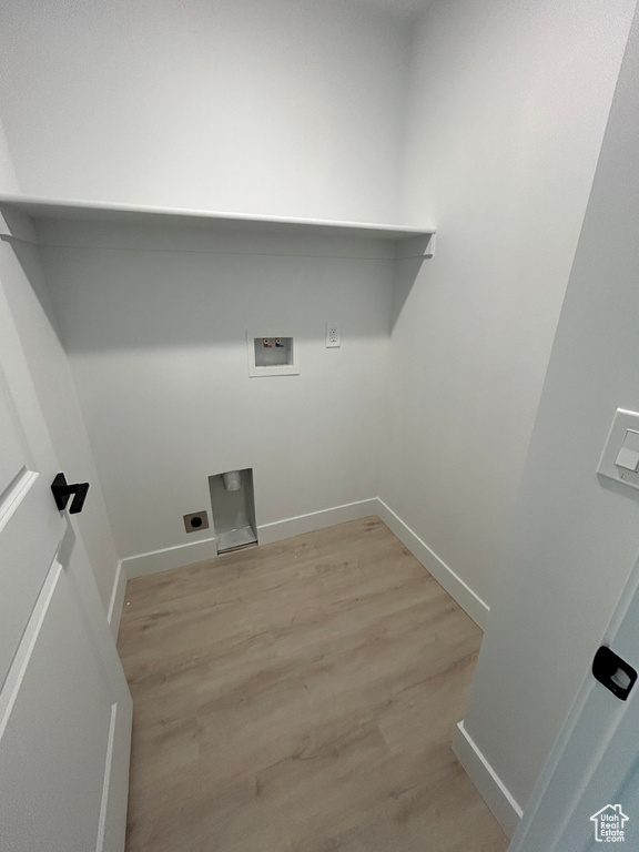 Laundry room with hookup for a washing machine, light wood-style floors, and baseboards