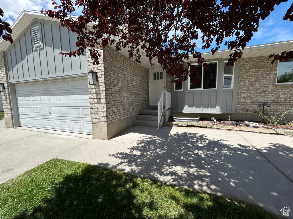 View of front of house with board and batten siding, brick siding, driveway, and a garage