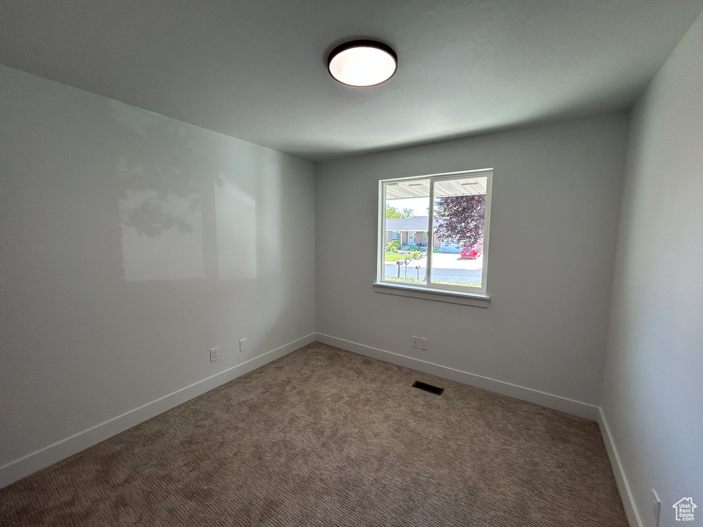 Carpeted spare room featuring baseboards
