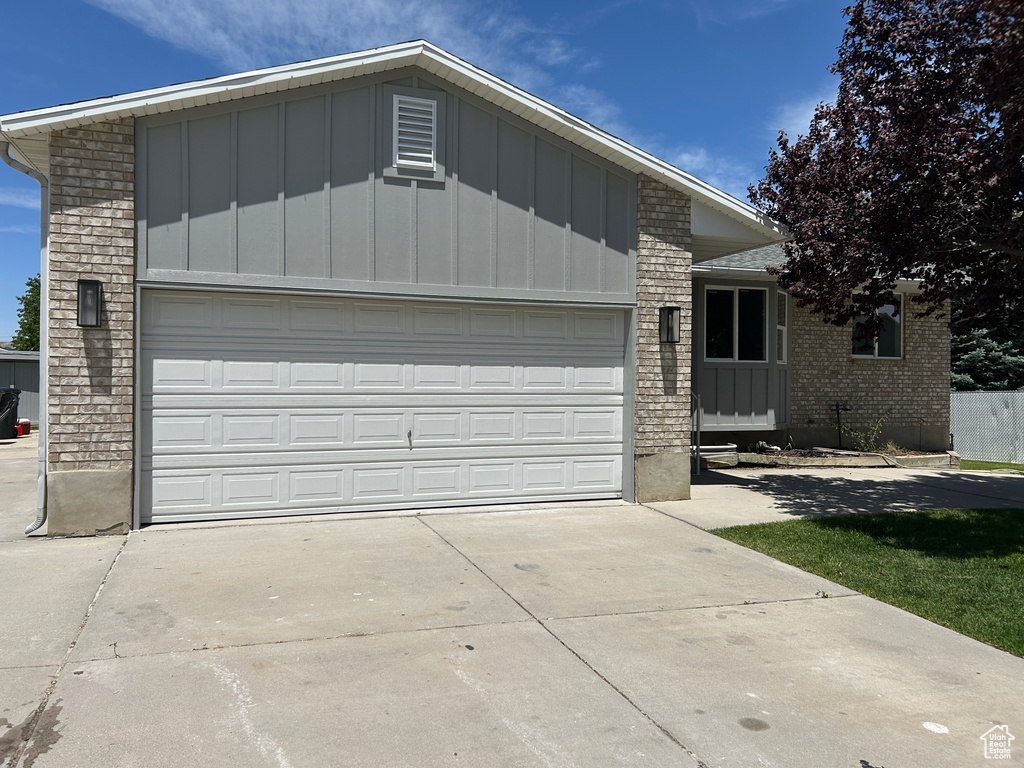 View of front facade featuring concrete driveway, board and batten siding, brick siding, and an attached garage