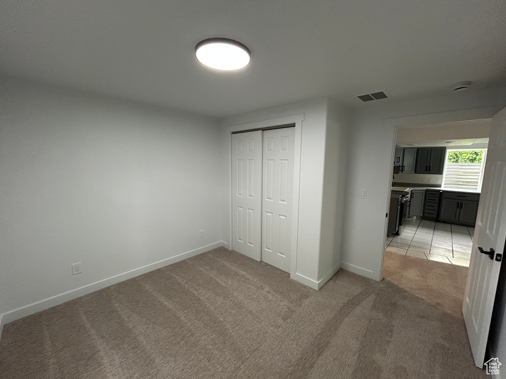 Unfurnished bedroom featuring light carpet and a closet