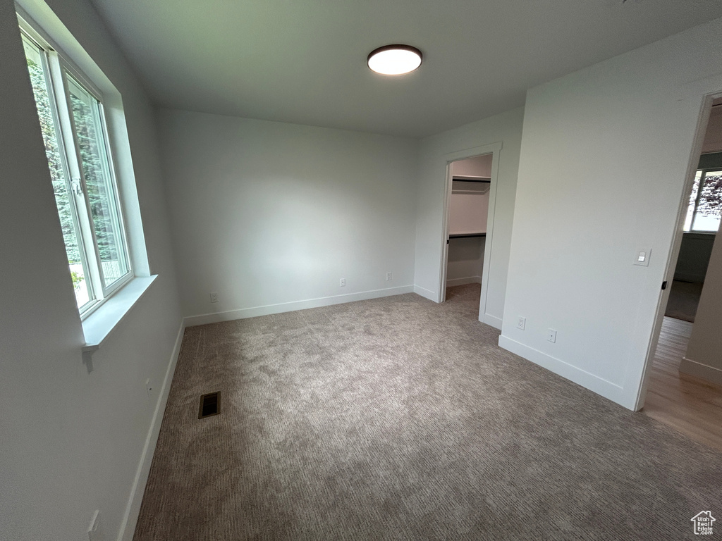 Unfurnished bedroom featuring carpet, a spacious closet, and a closet