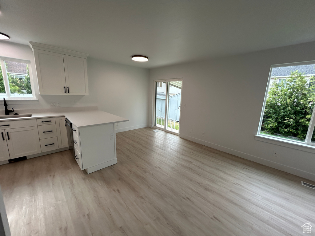Kitchen featuring light wood-style floors, a peninsula, light countertops, and healthy amount of natural light