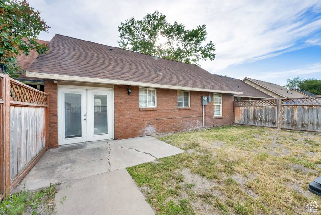 Back of house featuring french doors, brick siding, a fenced backyard, a patio area, and roof with shingles