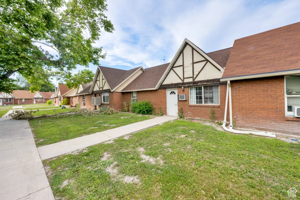 Tudor house featuring brick siding, a front lawn, and a shingled roof