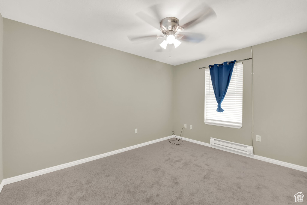 Carpeted empty room featuring baseboard heating and ceiling fan