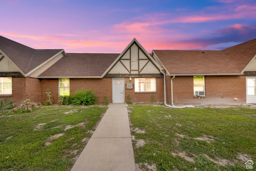 View of front of home featuring brick siding, a front yard, roof with shingles, and cooling unit