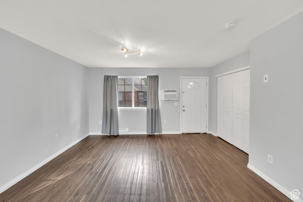 Unfurnished living room with dark wood finished floors and a wall mounted AC