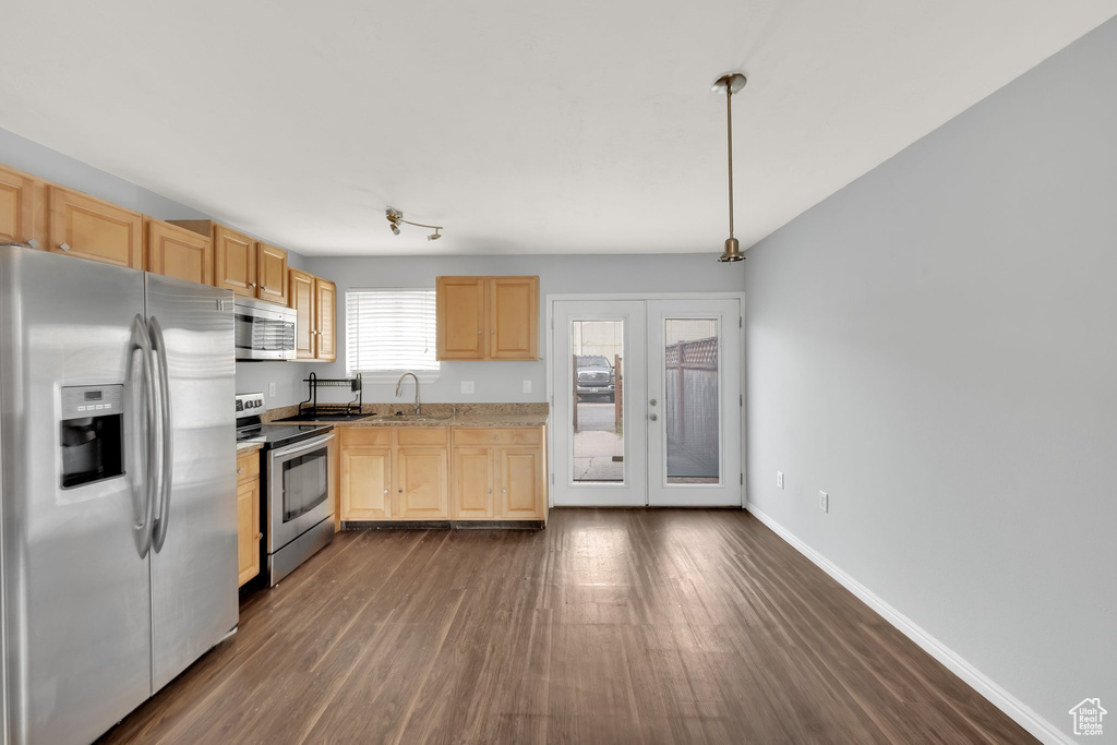 Kitchen with stainless steel appliances, light brown cabinets, dark wood finished floors, light countertops, and pendant lighting