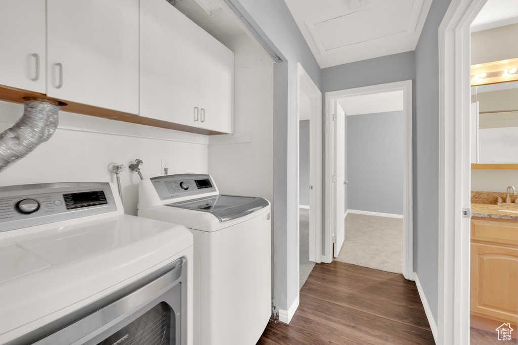 Washroom with separate washer and dryer, dark wood-type flooring, and cabinet space