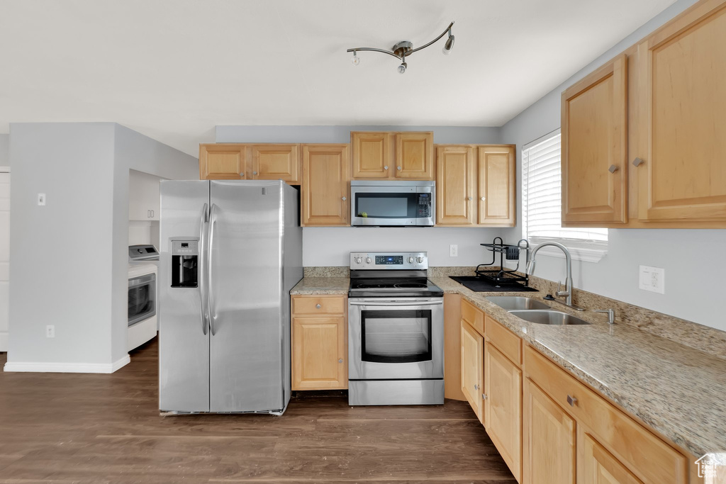 Kitchen with stainless steel appliances, light brown cabinetry, and washer / clothes dryer