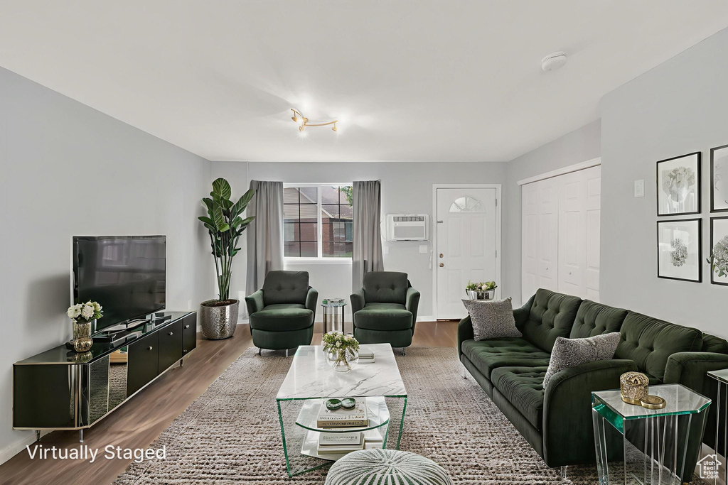 Living area with wood finished floors and a wall unit AC