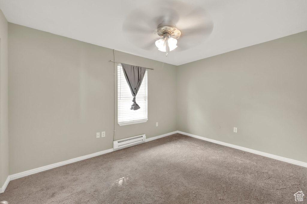 Carpeted spare room featuring baseboard heating and ceiling fan
