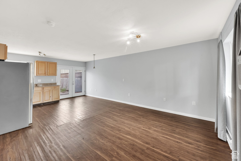 Unfurnished living room featuring dark wood-style floors and baseboards