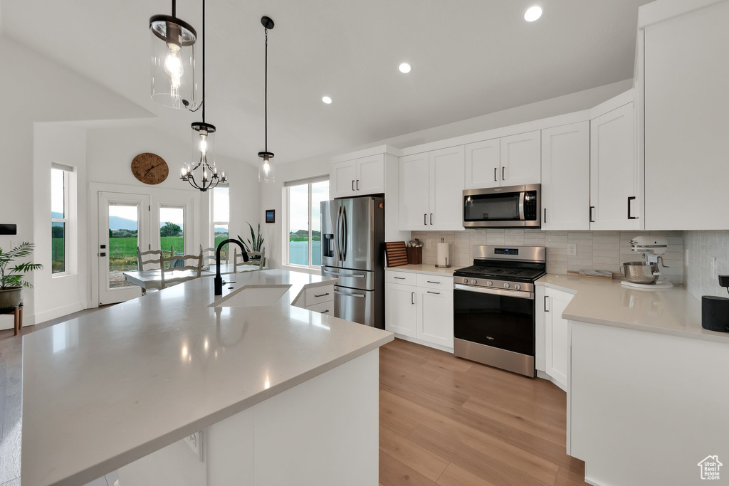 Kitchen featuring stainless steel appliances, light wood-style floors, light countertops, decorative backsplash, and recessed lighting