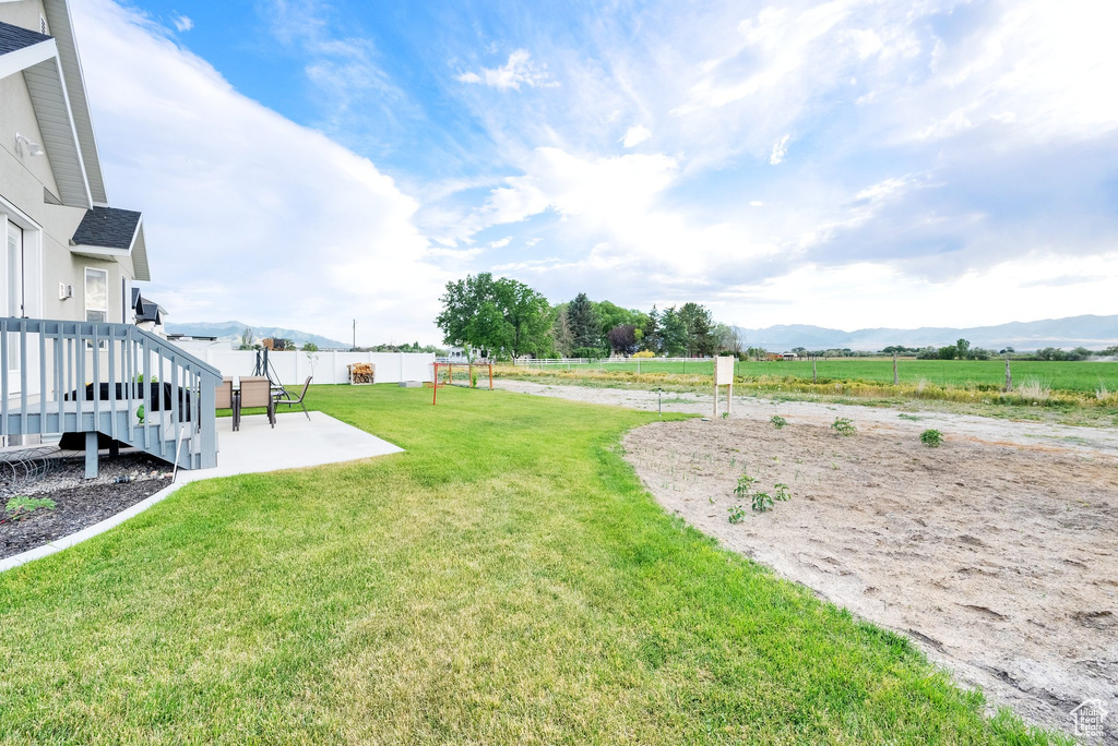 View of yard with a view of countryside, a patio, and a deck with mountain view