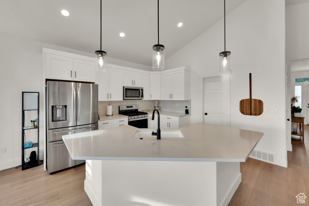 Kitchen featuring appliances with stainless steel finishes, light wood-style floors, backsplash, light countertops, and recessed lighting