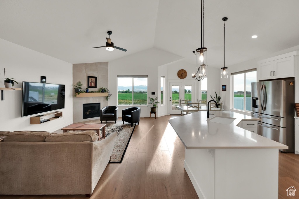 Living area with a ceiling fan, lofted ceiling, a fireplace, light wood-type flooring, and recessed lighting