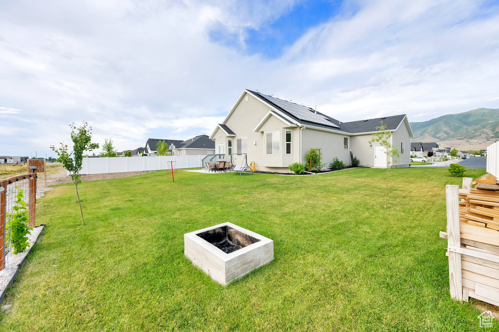 Fenced backyard featuring an outdoor fire pit, a patio area, and a mountain view