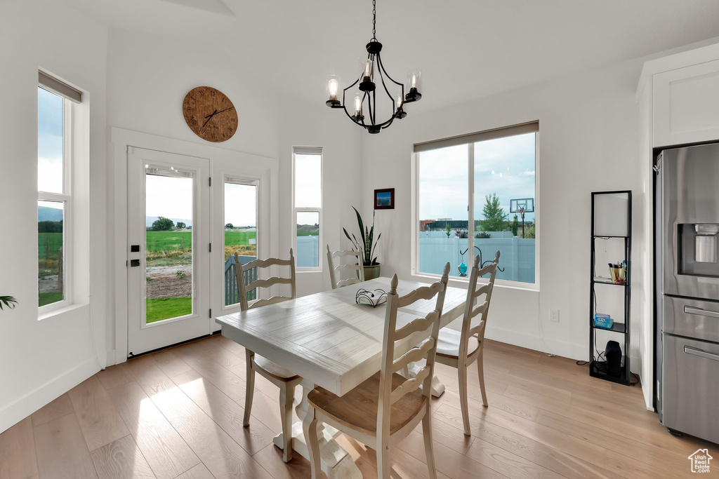 Dining area with light wood-style flooring, a chandelier, and vaulted ceiling