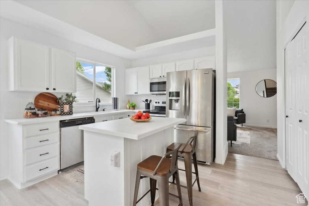 Kitchen featuring appliances with stainless steel finishes, a breakfast bar area, white cabinetry, and a center island