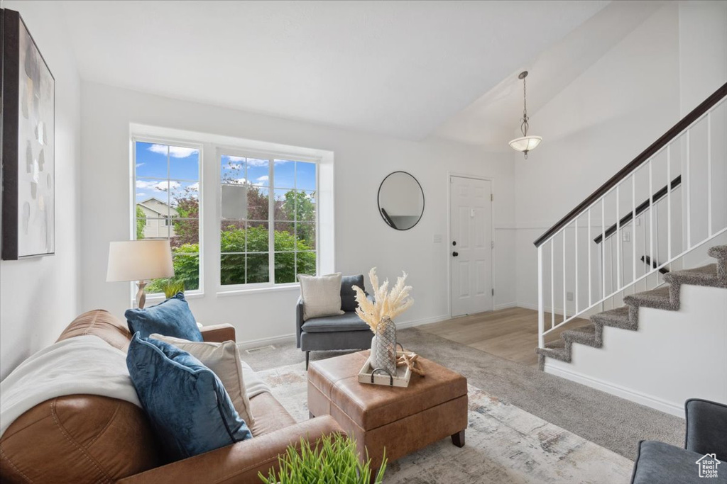 Living area featuring stairs, carpet, and vaulted ceiling