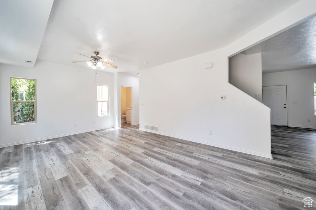 Empty room with wood finished floors, plenty of natural light, and a ceiling fan