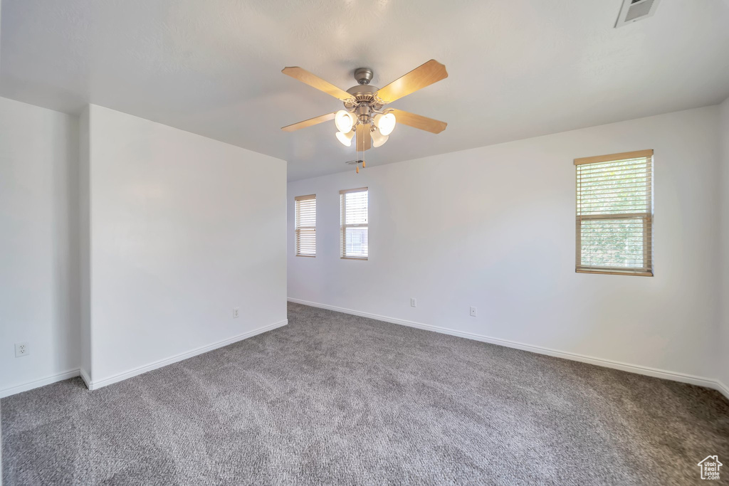 Empty room with healthy amount of natural light, carpet floors, and ceiling fan