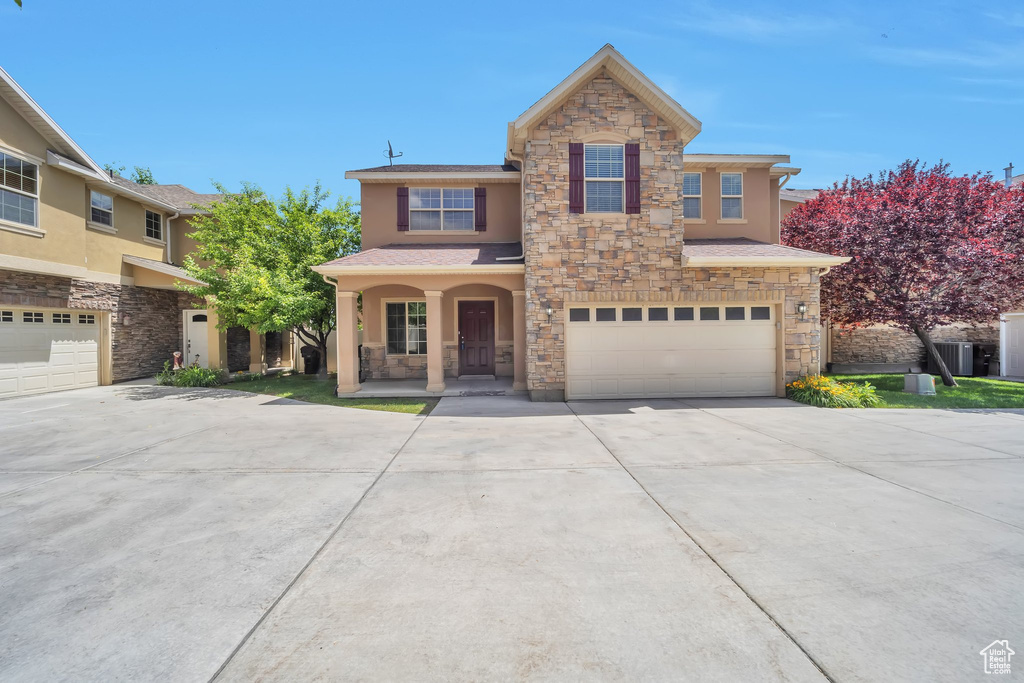 Traditional-style home with stone siding, stucco siding, concrete driveway, and an attached garage