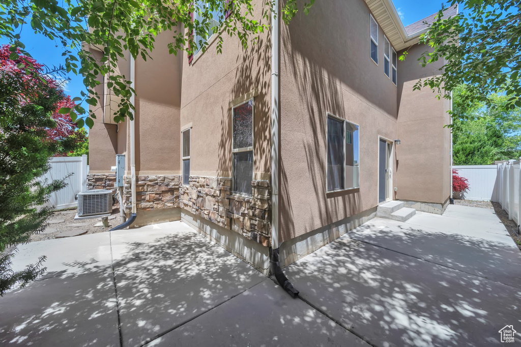 View of property exterior with stucco siding, a patio, a fenced backyard, and stone siding