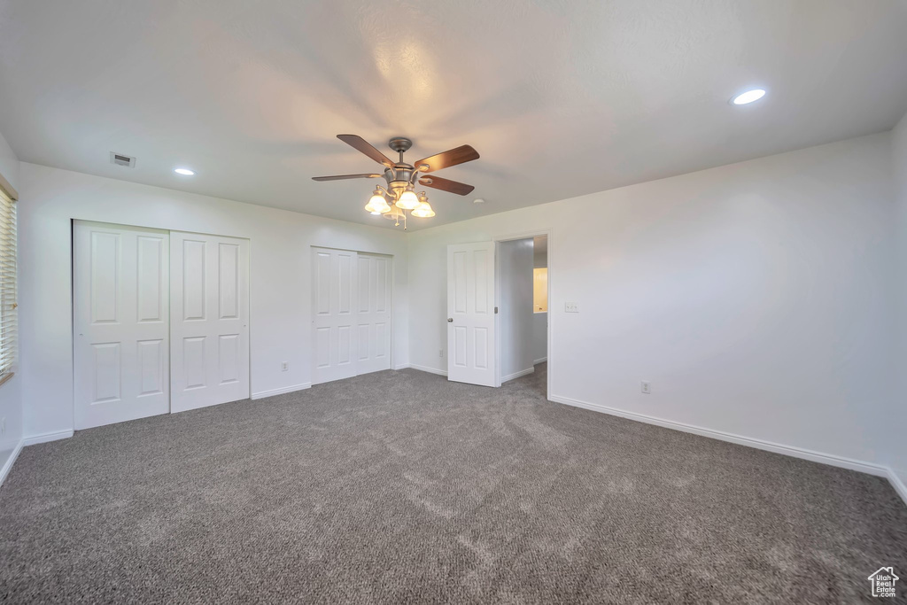 Unfurnished bedroom featuring multiple closets, dark colored carpet, recessed lighting, and a ceiling fan