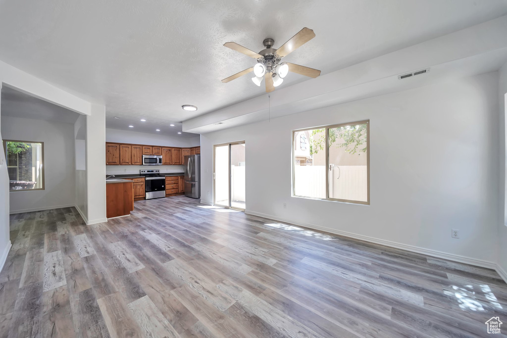 Unfurnished living room featuring light wood-style flooring, a ceiling fan, and recessed lighting