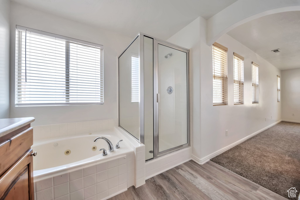 Bathroom with vanity, a whirlpool tub, a stall shower, and wood finished floors