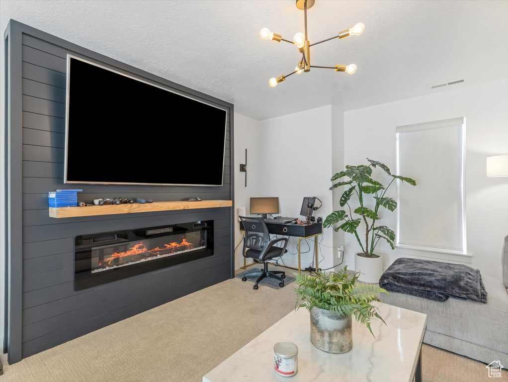 Carpeted living room with a chandelier, a glass covered fireplace, and an office area