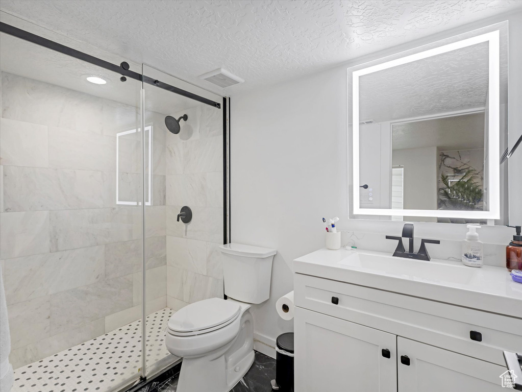 Bathroom with vanity, a stall shower, and a textured ceiling